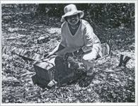 Woman in white kneels next to a headstone