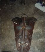 Steel Sculpture of Tribal Mask Lying on Concrete Floor with Fan Eyebrows