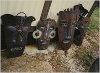 4 Steel Sculptures of Tribal Masks Leaning Against a Shed