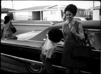 Unidentified Boy and Woman Stand by a Cadillac, circa 1972