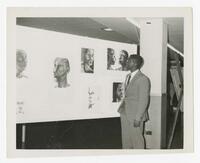 An Unidentified Man at Wall of Portraits at an Art Exhibits, circa 1965