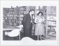 Photograph of Mildred L. Terry showing John R. Bannister a book in the Fourth Avenue Library, Columbus, Georgia