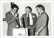Photograph of three men standing behind a podium outfitted with a microphone, Clarkesville, Habersham County, Georgia