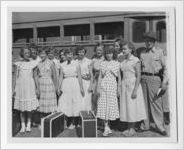 Photograph of girls standing with a state trooper in front of a school bus, Clarkesville, Habersham County, Georgia, 1953