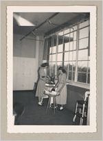 Photograph of young women viewing items placed on small tables inside a classroom, Clarkesville, Habersham County, Georgia, 1953