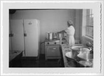 Photograph of a woman grabbing a pot on a stove, Clarkesville, Habersham County, Georgia, 1953