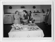 Photograph of two women gathered together at a punch bowl while others look on, Clarkesville, Habersham County, Georgia, 1953