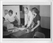 Photograph of a group of people taking notes while meeting at a desk, Clarkesville, Habersham County, Georgia, 1953