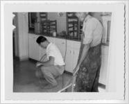 Photograph of two men handling a cable inside of a kitchen, Clarkesville, Habersham County, Georgia, 1953