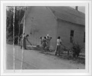 Photograph of African American men and women raking land by a wooden building, Clarkesville, Habersham County, Georgia, 1953
