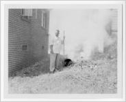 Photograph of a man burning waste next to a building, Clarkesville, Habersham County, Georgia, 1953