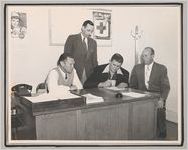 Photograph of four men gathered around desk inside an office, Clarkesville, Habersham County, Georgia, 1950