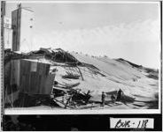 [Photograph of men looking at the remains of a temporary warehouse attached to a grain elevator, Waynesboro, Burke County, Georgia, 1961]