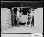 [Photograph of E. D. Gill, B. B. Lovett, Sr., and Henry Hegman weighing cotton, Woodbury, Meriwether County, Georgia, ca. 1925]