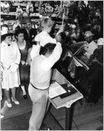 [Photograph of a child standing on podium conducting a band at the launching of the Liberty ship Henry W. Grady, J.A. Jones Construction Company shipyard, Brunswick, Georgia, 1943 Oct. 22?]
