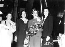 [Photograph of Mona Douglas, Mrs. Alfred W. Jones, Dorothy Torras and Dorothy Rogers standing on a podium at the christening of the Liberty ship Howard E. Coffin, J.A. Jones Construction Company shipyard, Brunswick, Georgia, 1944 Jan. 21?]