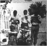 [Photograph of an African American man (with pet raccoon?) and four boys eating watermelon in a yard in or near Richmond County, Ga., in late 19th century]