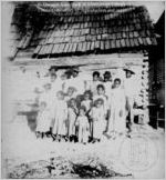 [Photograph of a group of young African American men, women, and children standing in front of a log cabin in or near Richmond County, Georgia, late 19th century]