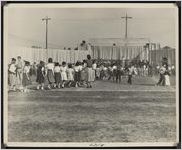 Photograph of children with hats on walking on the field at the Sylvester High School stadium during the Worth County Centennial Celebration in Sylvester, Worth County, Georgia, 1953 October