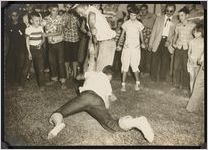 Photograph of a young person and an unknown man fighting over a "greased pig" as the crowd watches on during the Worth County Centennial Celebration in Sylvester, Worth County, Georgia, 1953 October