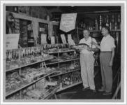 Photograph of men standing in front of the fishing equipment section of a store, Manchester, Georgia, 1953