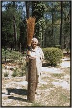Rural crafts: Johnnie Ree Jackson. Johnnie Ree Jackson stands in front yard with pine cone vase and broom sage broom