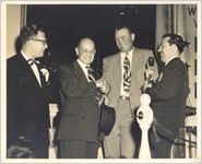 Photograph of Johnny Mize with three unidentified men in suits with a microphone