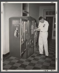 Candid campus photographs with unidentified individuals - Worker changing price of Coke from 5 cents to 6 cents at vending machine