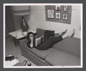 Students studying, 1960s - Student lying on dormitory lounge couch studying
