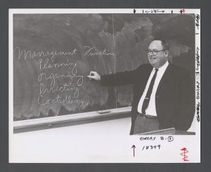 Business School - Professor writes on chalkboard