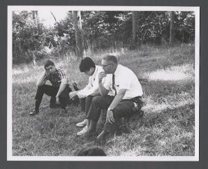 Freshman camp - Students and professor sitting on a log