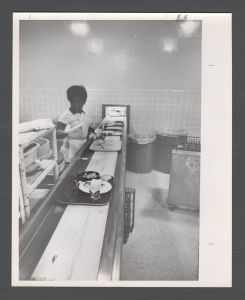 Cox Hall - Woman cleans trays from cafeteria line