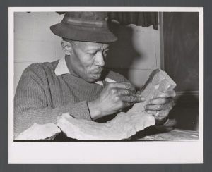Faculty and staff, unidentified individuals - Custodian whittling a block of wood
