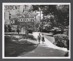 Student government elections, 1950s - Students hold hands as they walk under campaign banners