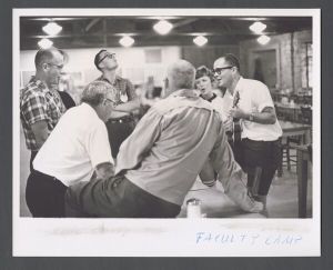 Faculty Camp - Professors sing around a table with a ukulele