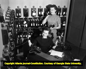 Answering service secretaries answer a room of telephones, 1955