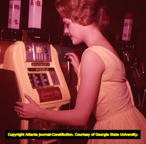 Las Vegas showgirl trying her luck on a slot machine, 1962
