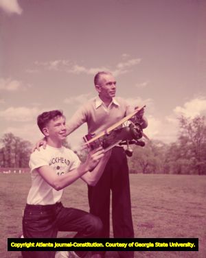 Father and son with the Buckhead Model Club race model airplanes in a field, 1951