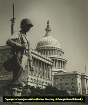 Solider holding riffle with bayonet, standing guard, Washington, D.C., United States Capitol Building in background, 1940s?