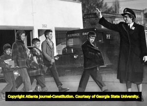 Atlanta policewomen safetly escorts children across a street, 1950