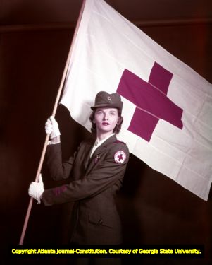 American Red Cross volunteer in uniform with the organization's flag, 1951