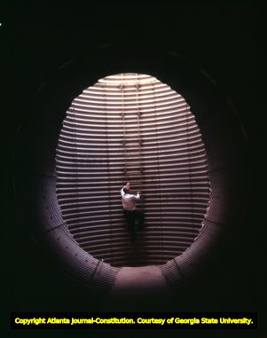 AT&T employee climbs an air vent at an underground office, 1967