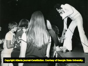 Elvis Presley leans over the stage to touch fans at concert at the Omni, Atlanta, Georgia, June 1976.