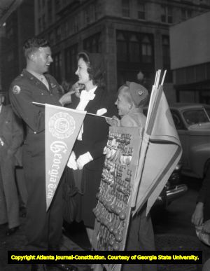 Young couple purchase a football button from a street stand, 1945