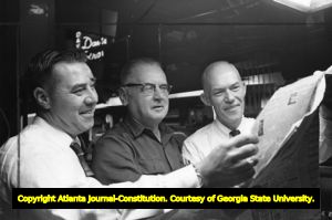 Cox Newspaper employees inspect the first run off the new press, 1966