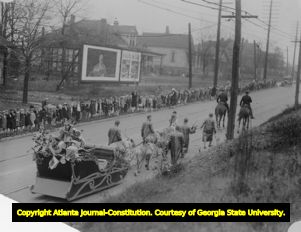 Children line the street to watch Santa Claus in a Christmas parade, 1920s