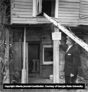 Director of Urban Renewal Department Malcolm D. Jones inspects a one-room apartment at 681 Dallas Street (Old Fourth Ward), Atlanta, Georgia, November 1961.