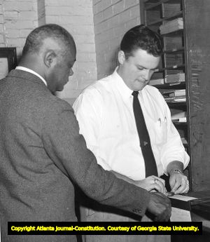 Reverand William Holmes Borders being processed by police after a segregated bus protest, 1957