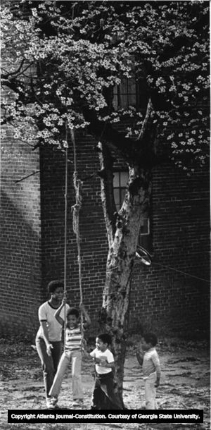 Mother pushes children in tree-swing, Techwood Homes, Atlanta, Georgia, March 17, 1982.