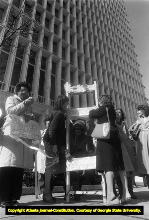 Atlanta Working Women display 'Ladder of Success' during a protest outside the Life of Georgia building, 1983